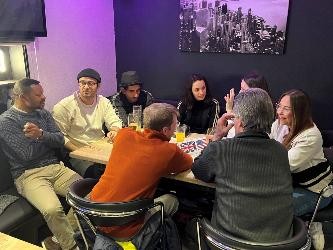 Mehrere Personen sitzen an einem Tisch und Unterhalten sich in verschiedenen Sprachen miteinander.