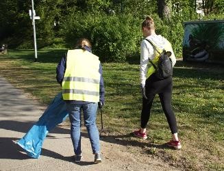 zwei Personen mit gelben Warnwesten sammel ausgerüstet mit Greifzange und Müllsack  Müll