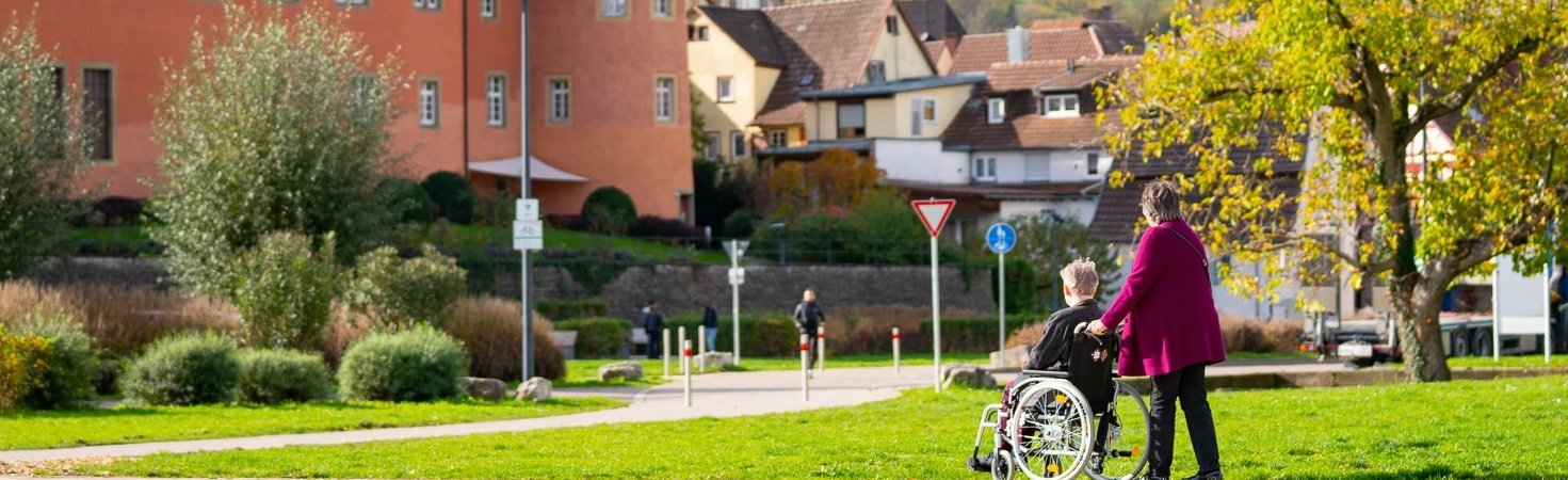 Ehrenamtsbörse. Foto Olivier Schniepp, Foto Linke GmbH. Eine Frau schiebt einen älteren Mann im Rollstuhl.