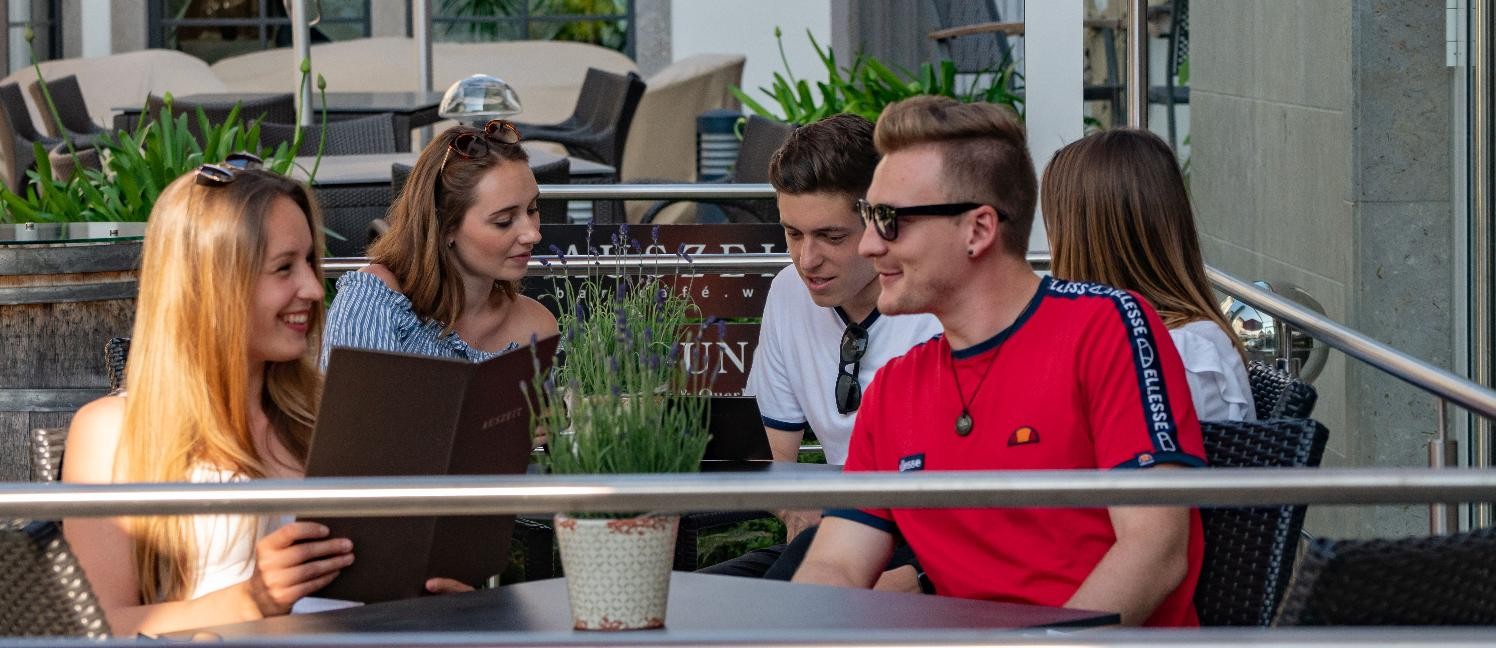 Menschen sitzen an Café-Tischen.