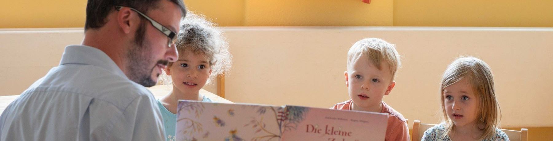 Kinderhaus Künzelsau. Foto Olivier Schniepp. Erzieher zeigt Kindern ein Buch.